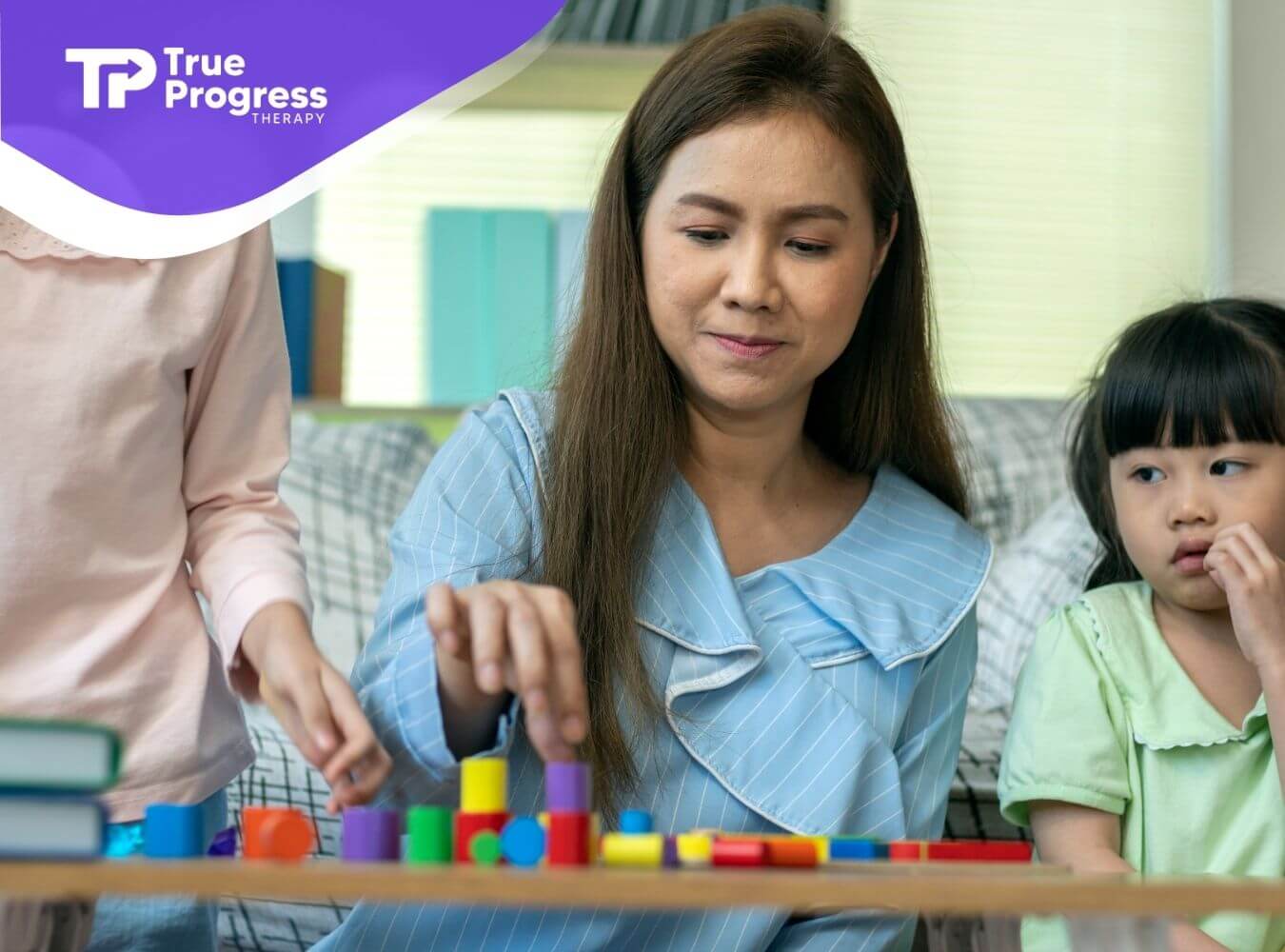 A therapist guiding two autistic kids during a structured learning activity using colorful blocks in a calm home setting