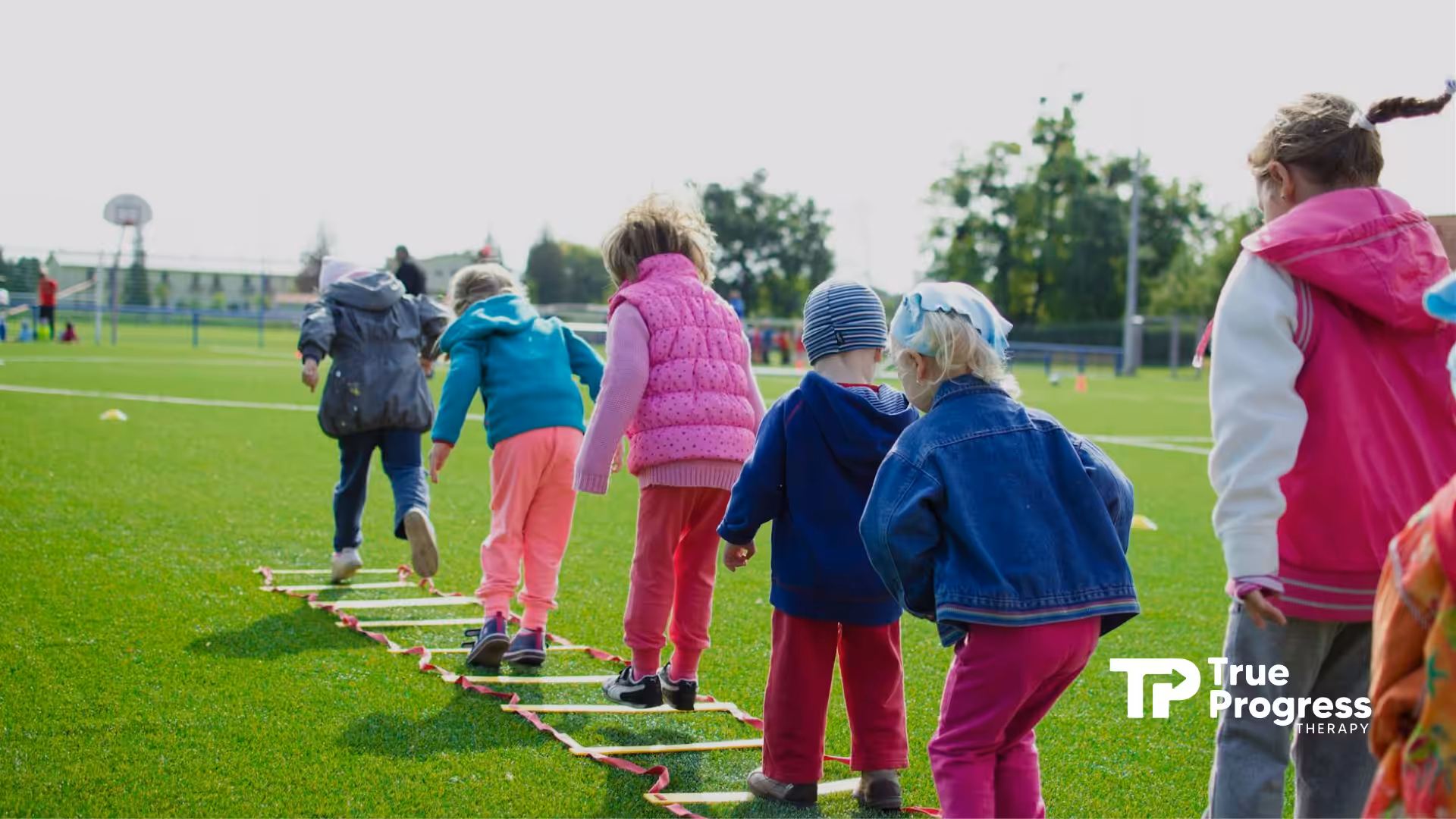 Autistic kids walking in line on sports field, balancing on ladder during outdoor activities in NJ.