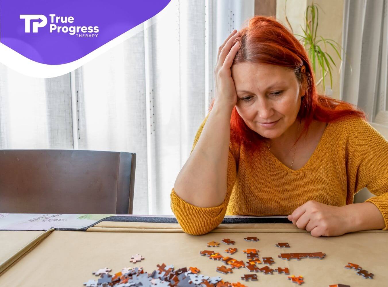 ABA therapist with red hair looking thoughtfully at scattered puzzle pieces on a table, showing problem solving & reflection.