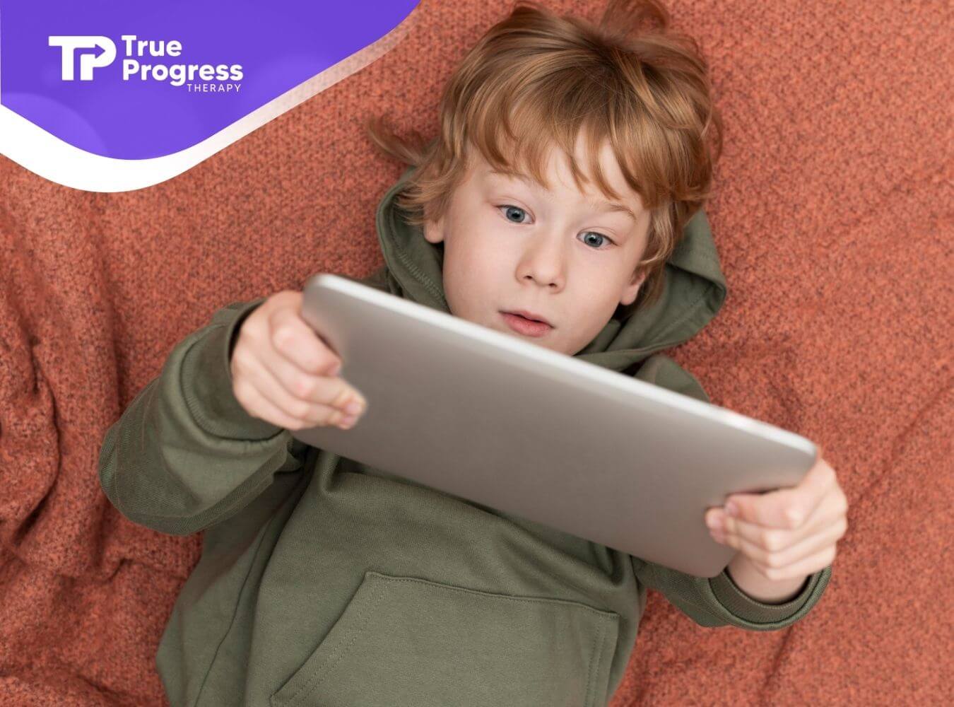 An autistic boy looking at an iPad screen.