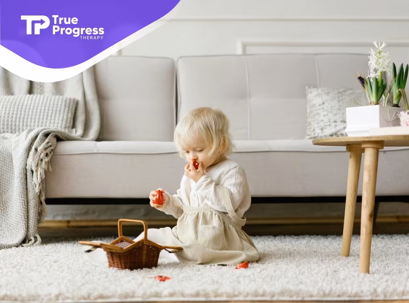 An autistic toddler sitting on a carpet eating strawberries from a basket during ABA therapy in New Jersey.
