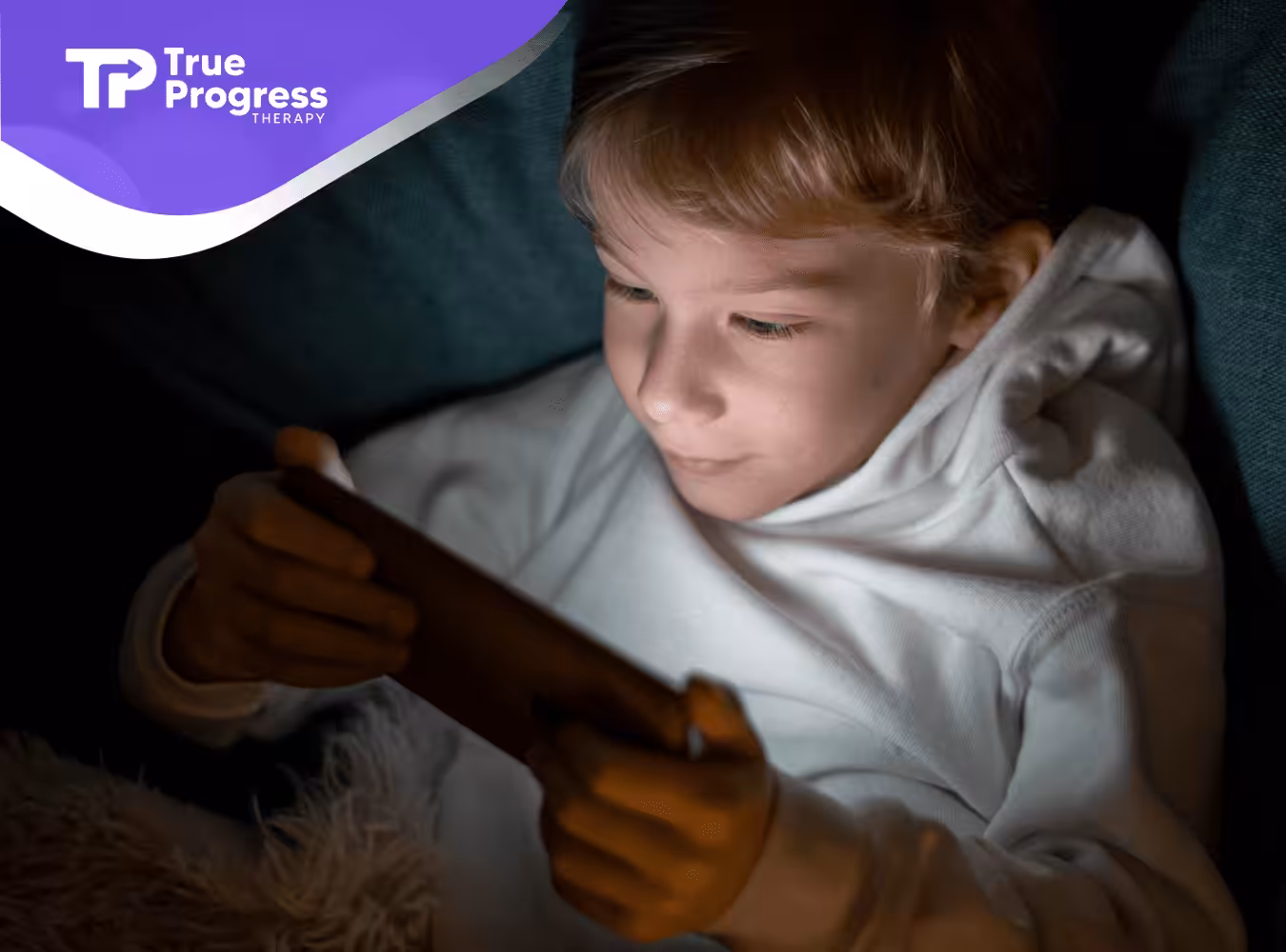 A boy using a smartphone in bed at night