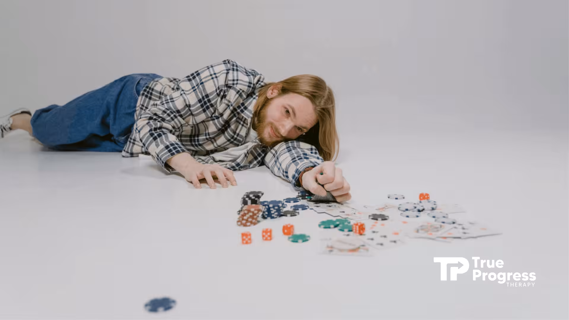 An autistic person lying on the floor, playing poker with chips and cards scattered around in New Jersey.