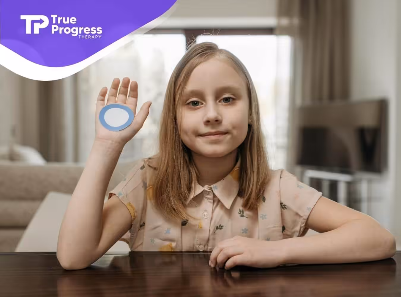 Individual holds up palm with blue circle in sunlit living room, wearing floral shirt and facing camera.