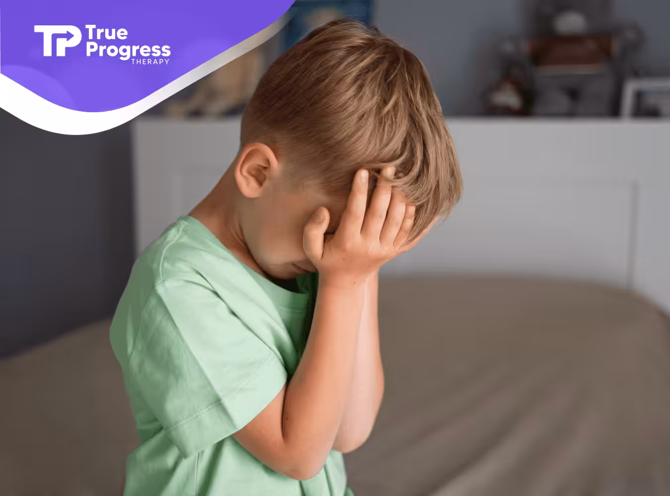 A boy with autism holding his face while upset