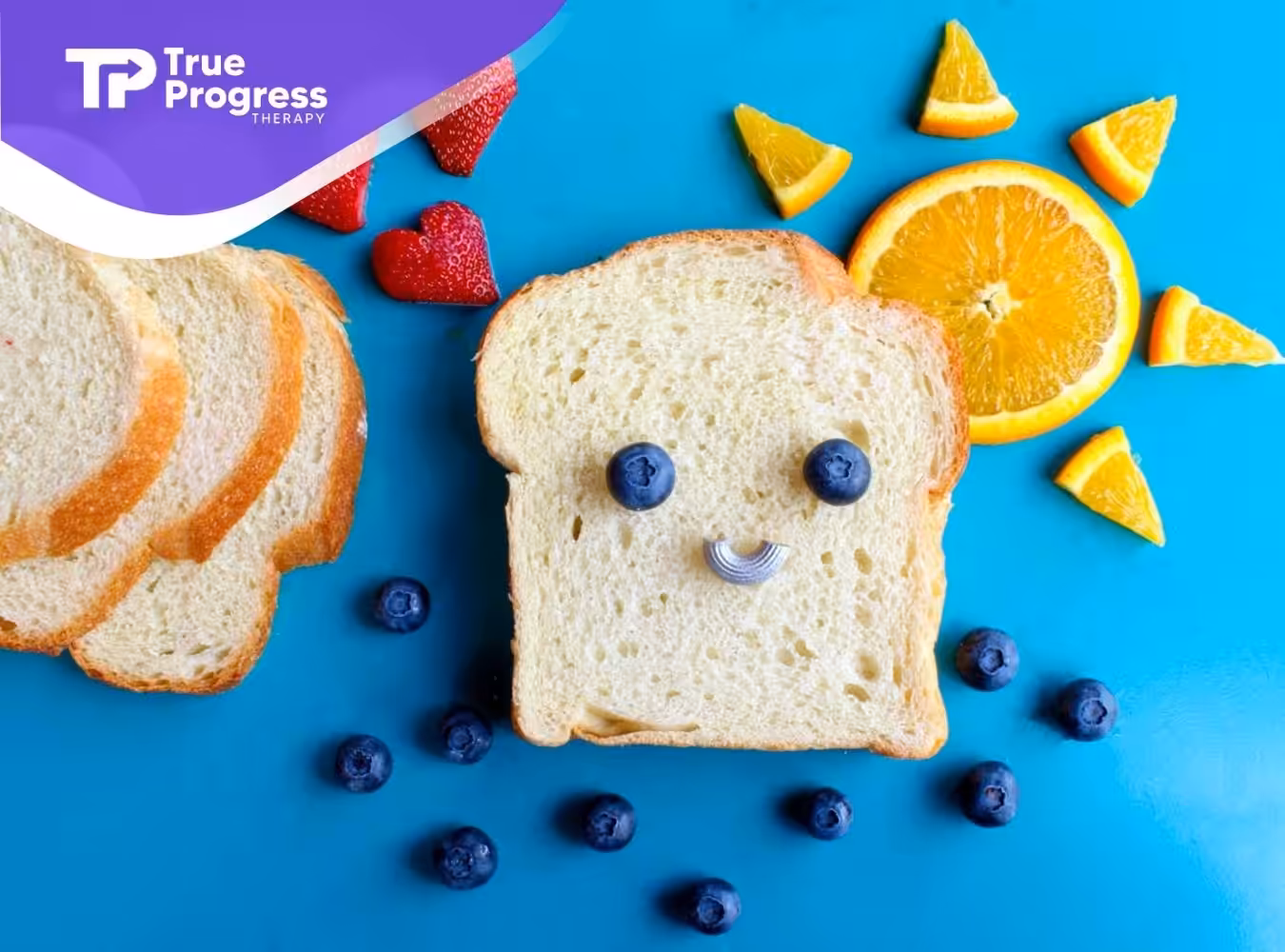Slices of bread, strawberries, blueberries, and oranges arranged on a blue surface in New Jersey.