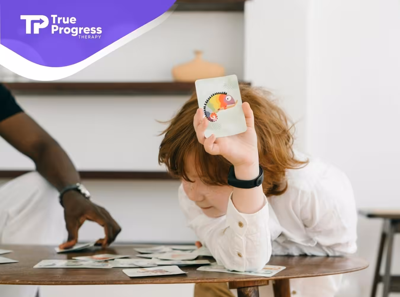 An autistic child holding up a card with a colorful chameleon during an ABA therapy session in New Jersey.