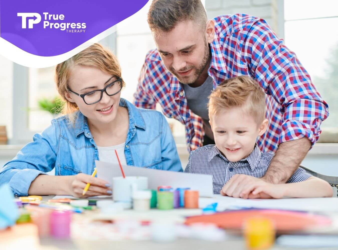 Two BCBA helping a young child with an art project at a table during ABA therapy.