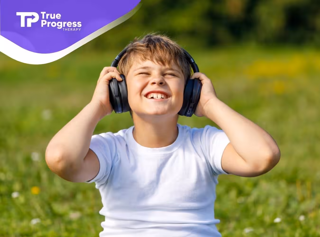 A smiling boy with autism is listening to music with headphones outdoors.