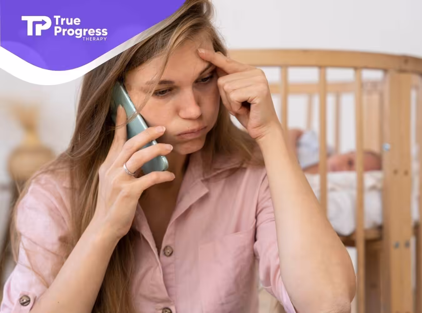 A stressed mother is talking on the phone while her baby with autism sleeps in a crib in the background.