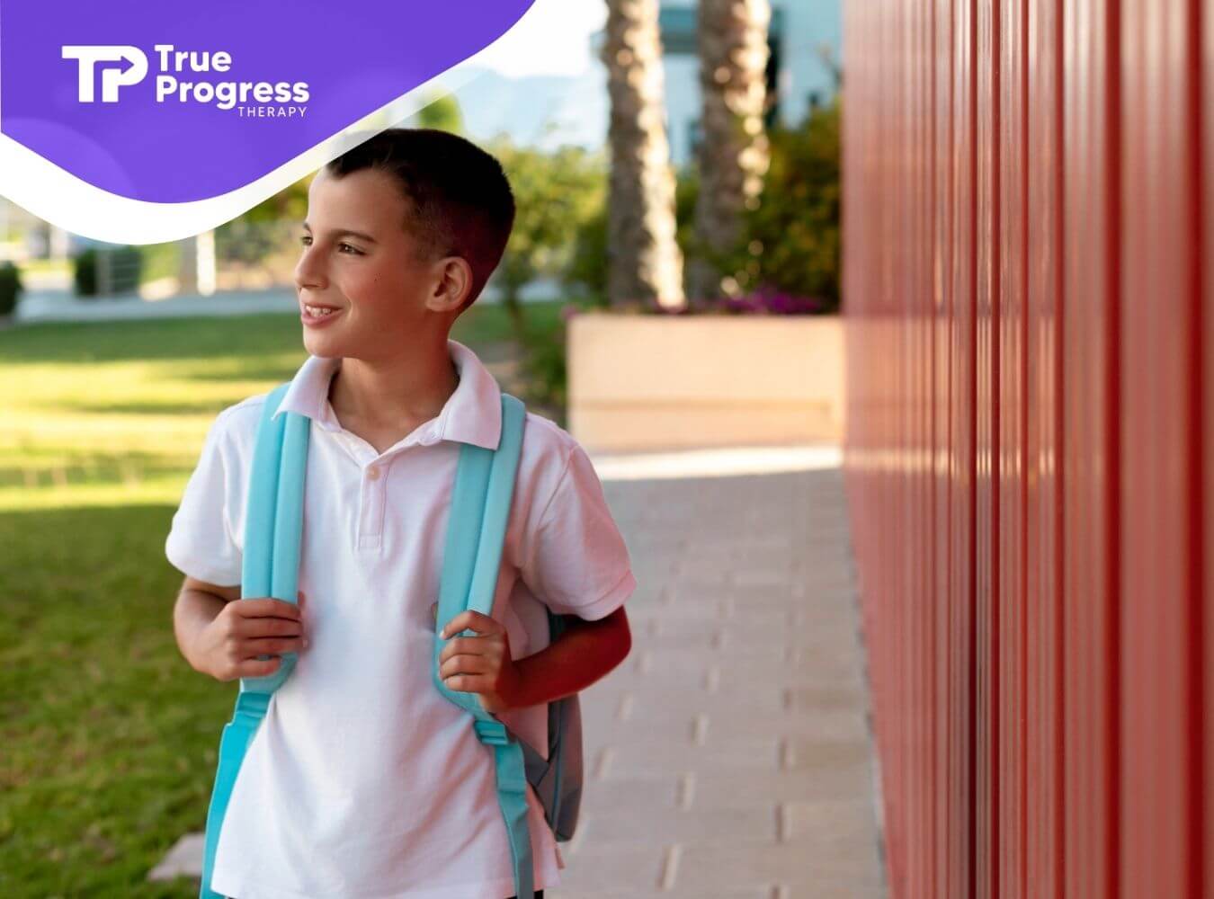 School-aged boy with a backpack standing outside near a building.