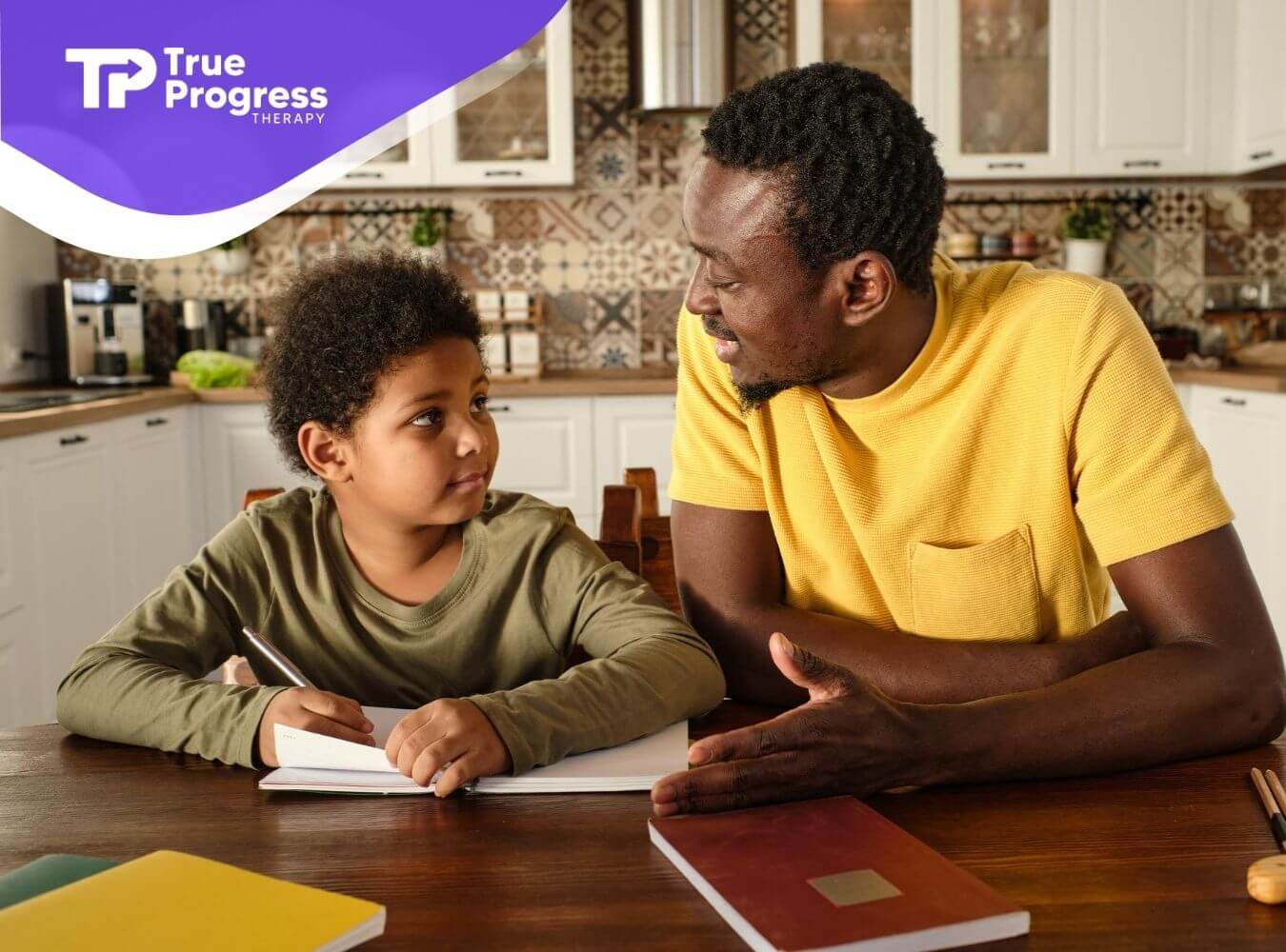 A BCBA helping autistic boy with homework at a kitchen table during in-home ABA.