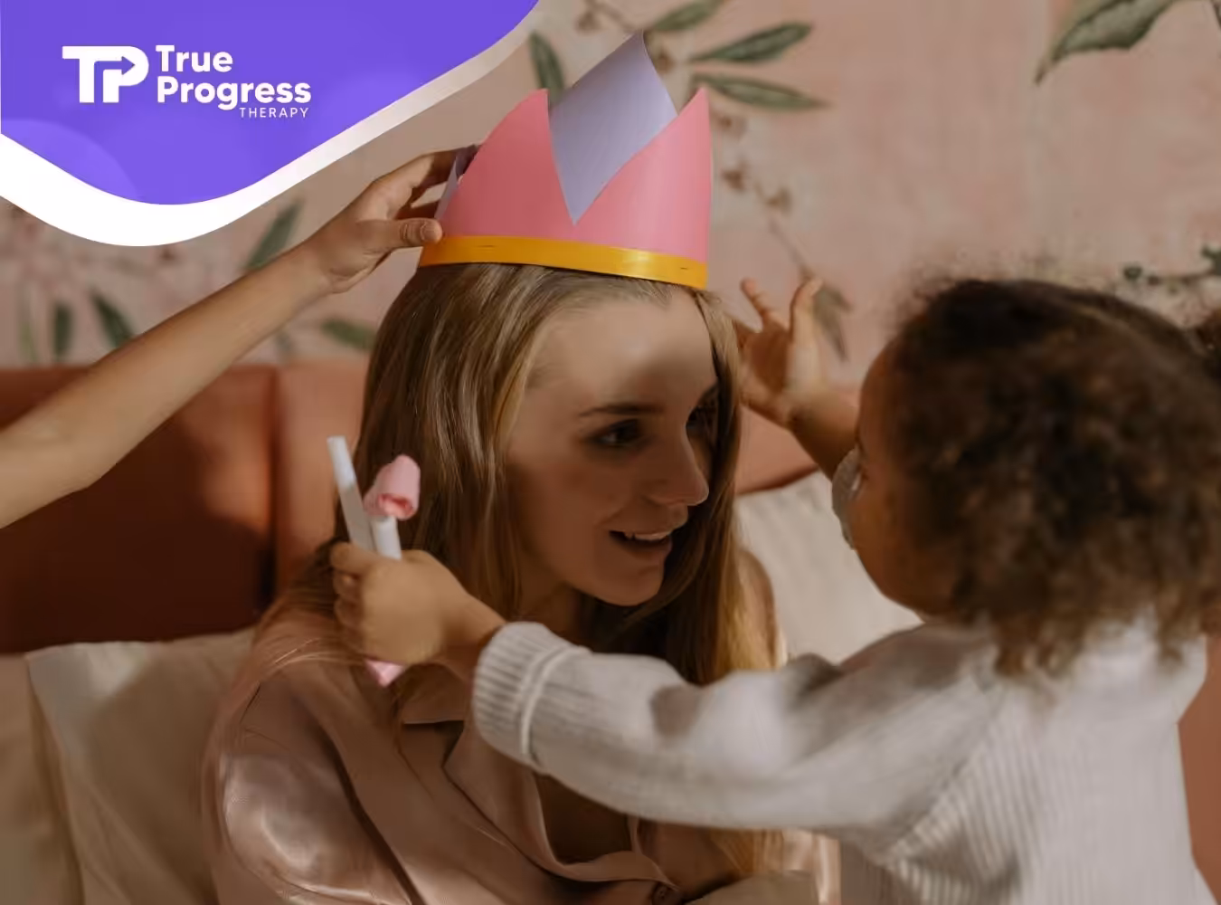 Autistic children placing a pink paper crown on their mother's head during ABA therapy session in New Jersey.