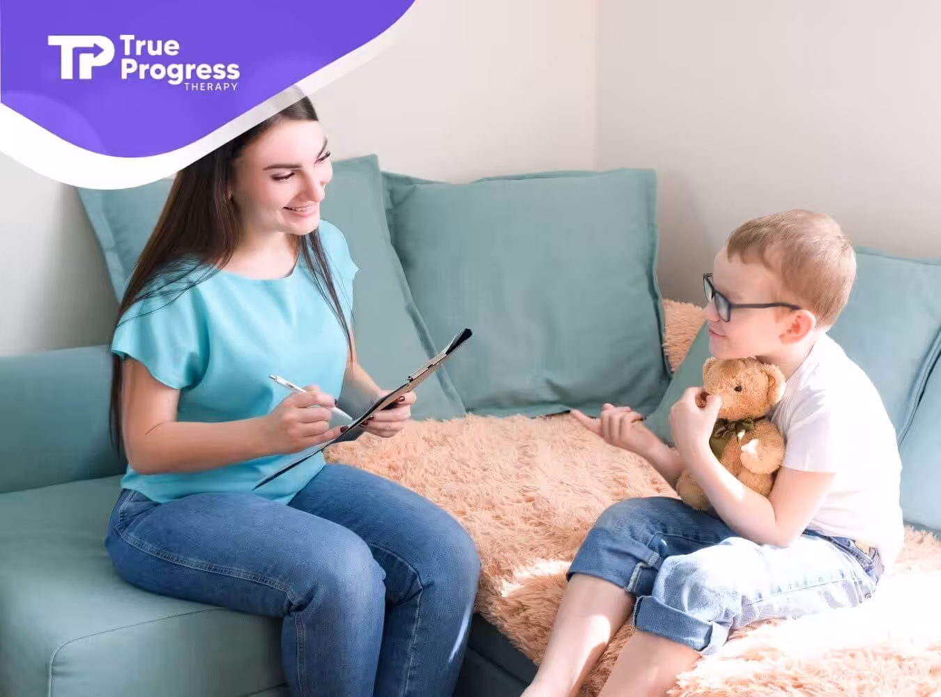 BCBA talking with young boy holding a teddy bear in ABA therapy.