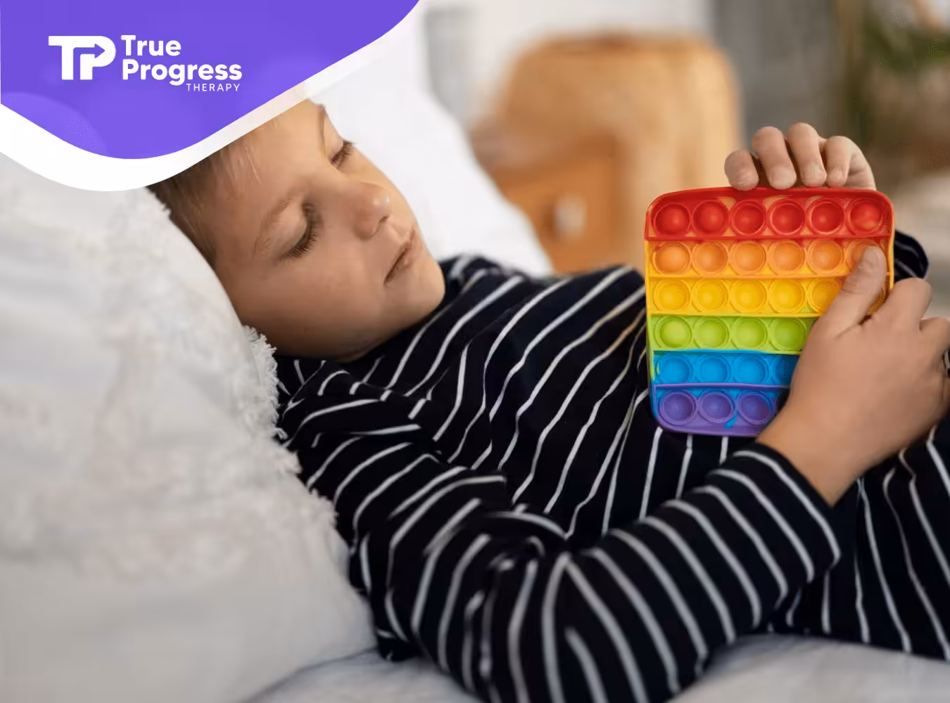 A boy lying on a bed holding a fidget toy