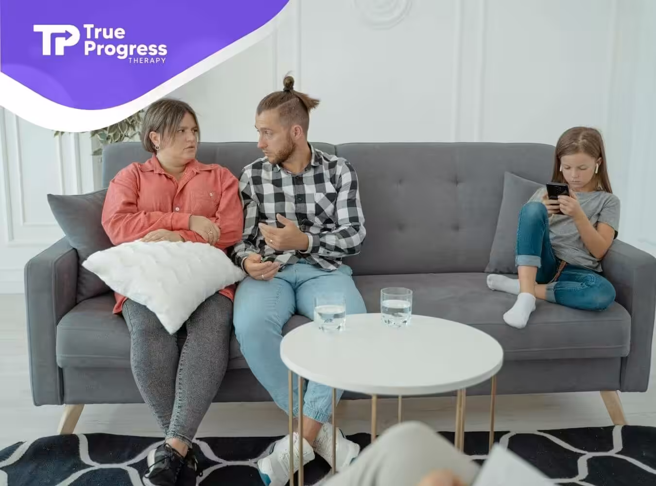The two ABA therapist sitting on a couch with a tense conversation and a child distracted after ABA therapy in New Jersey.