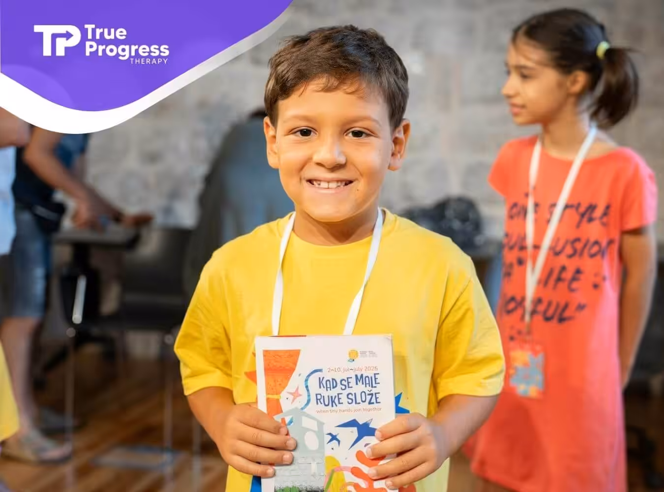 The autistic young boy smiling while holding a book at a children's event after ABA therapy in New Jersey.