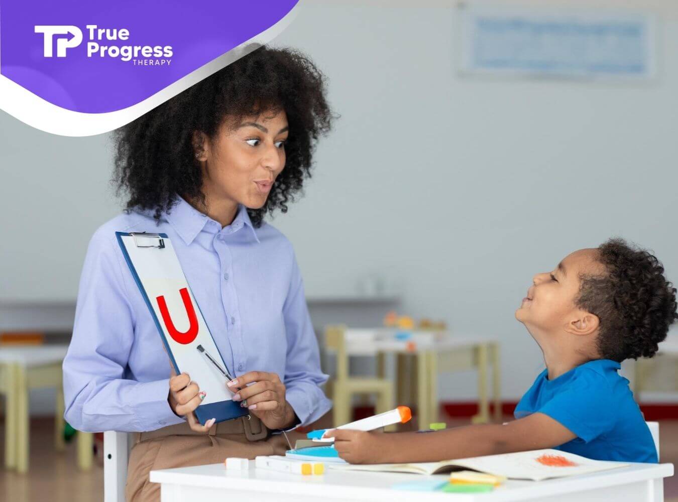 A BCBA showing a letter card to a child with autism during ABA therapy.