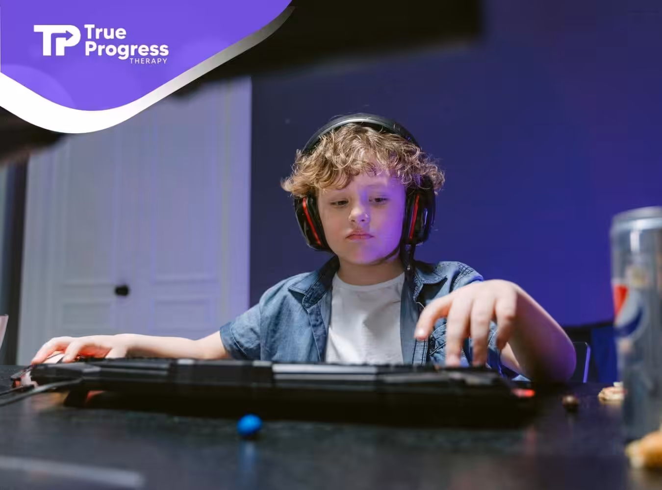 Autistic child wearing headset plays at desk with Pepsi and snacks, immersed in a glowing blue gaming setup.