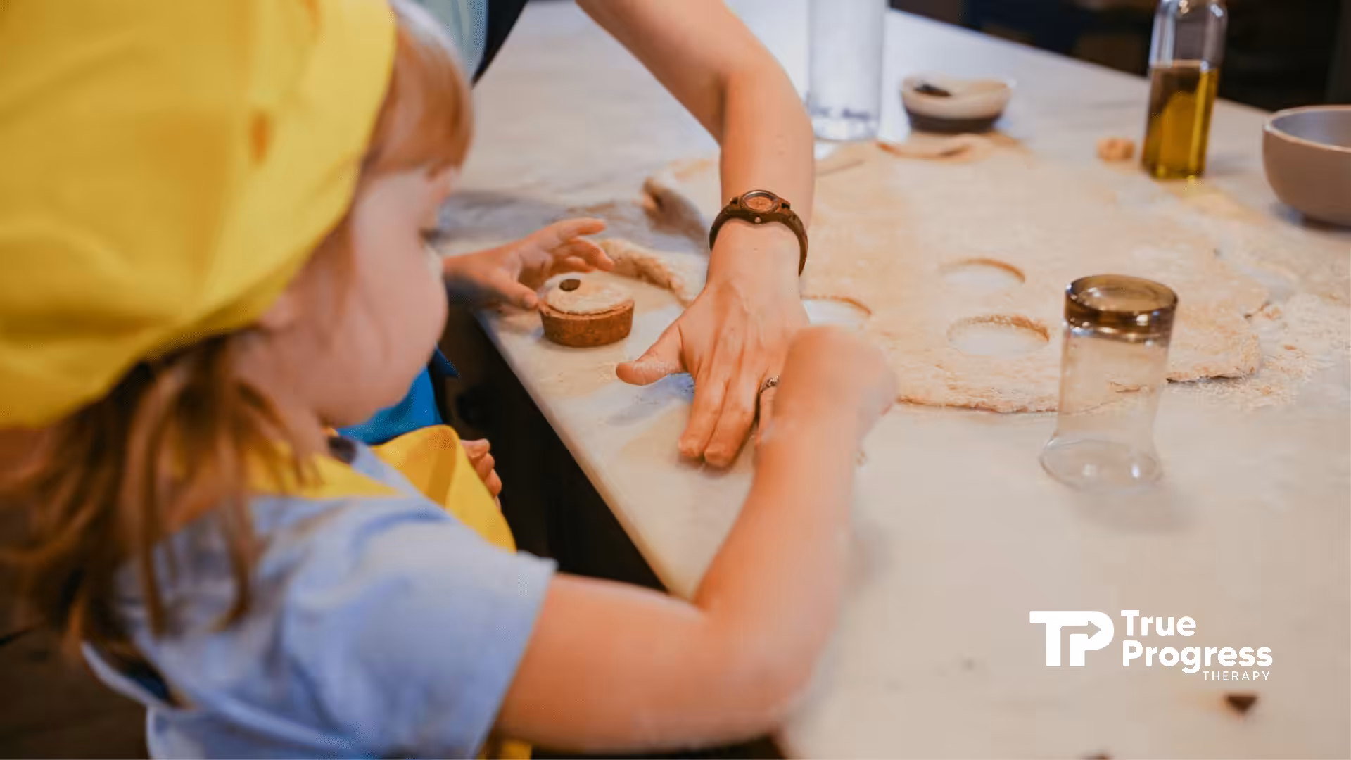 Autistic child and ABA therapist shaping dough together at a kitchen counter at home in New Jersey.