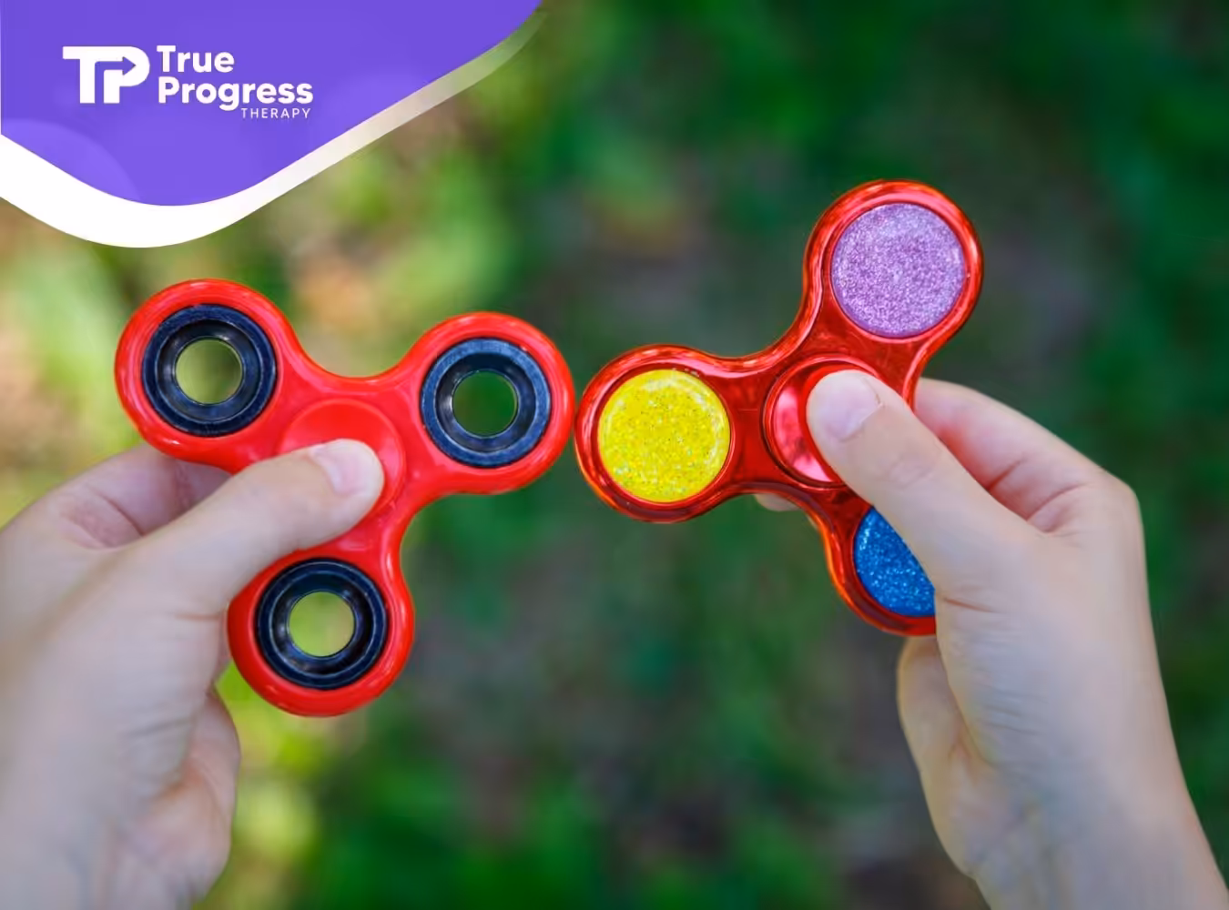 A close-up of two red fidget spinners held by a child's hands.