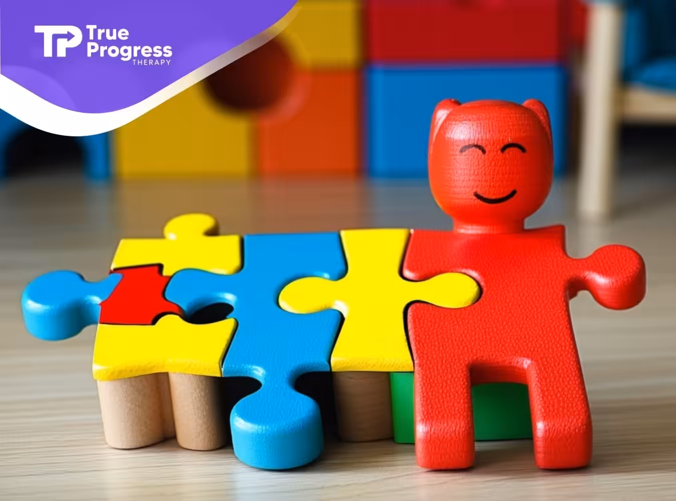 A red sensory toy with a smiling face sits beside a blue & yellow puzzle piece, representing autism.