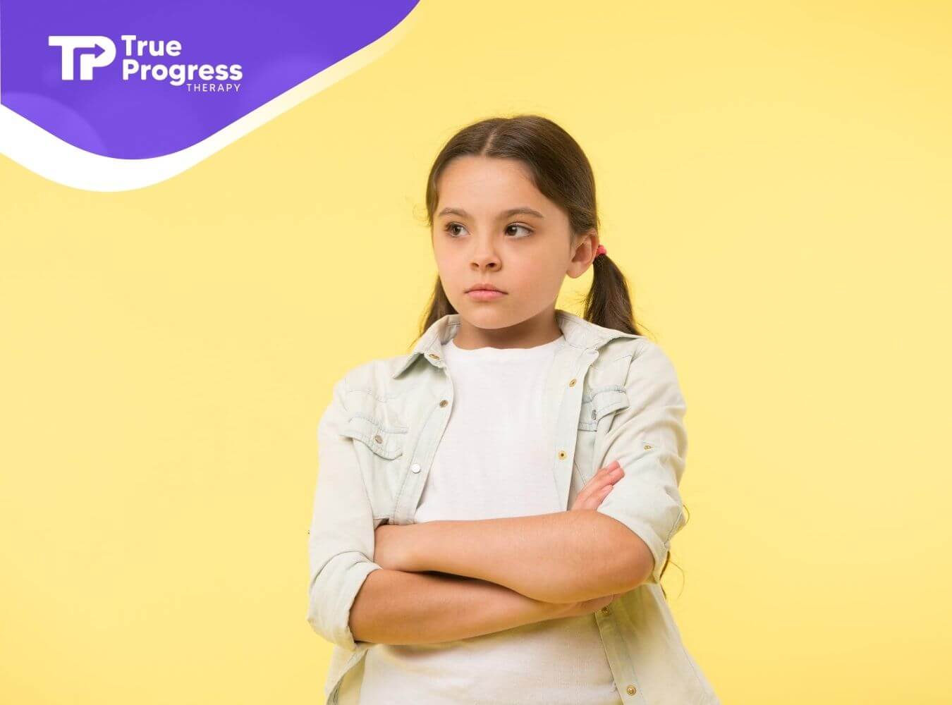 Autistic child standing with arms crossed against a yellow background in ABA therapy.
