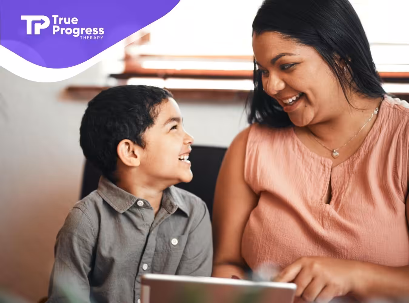 ABA therapist and and little boy smile at each other.