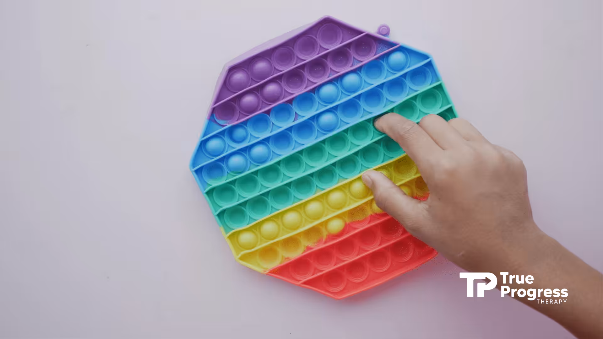 A close-up of a autistic child’s hand pressing bubbles on a therapeutic fidget pop-it toy in NJ.