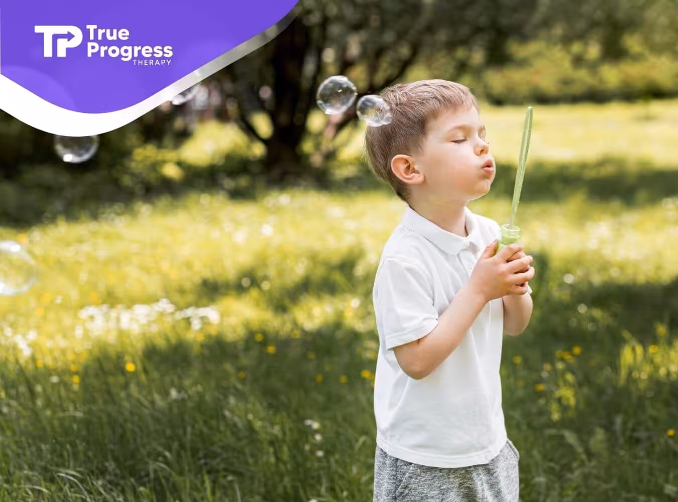 Autistic boy blowing soap bubbles outside after ABA therapy session.