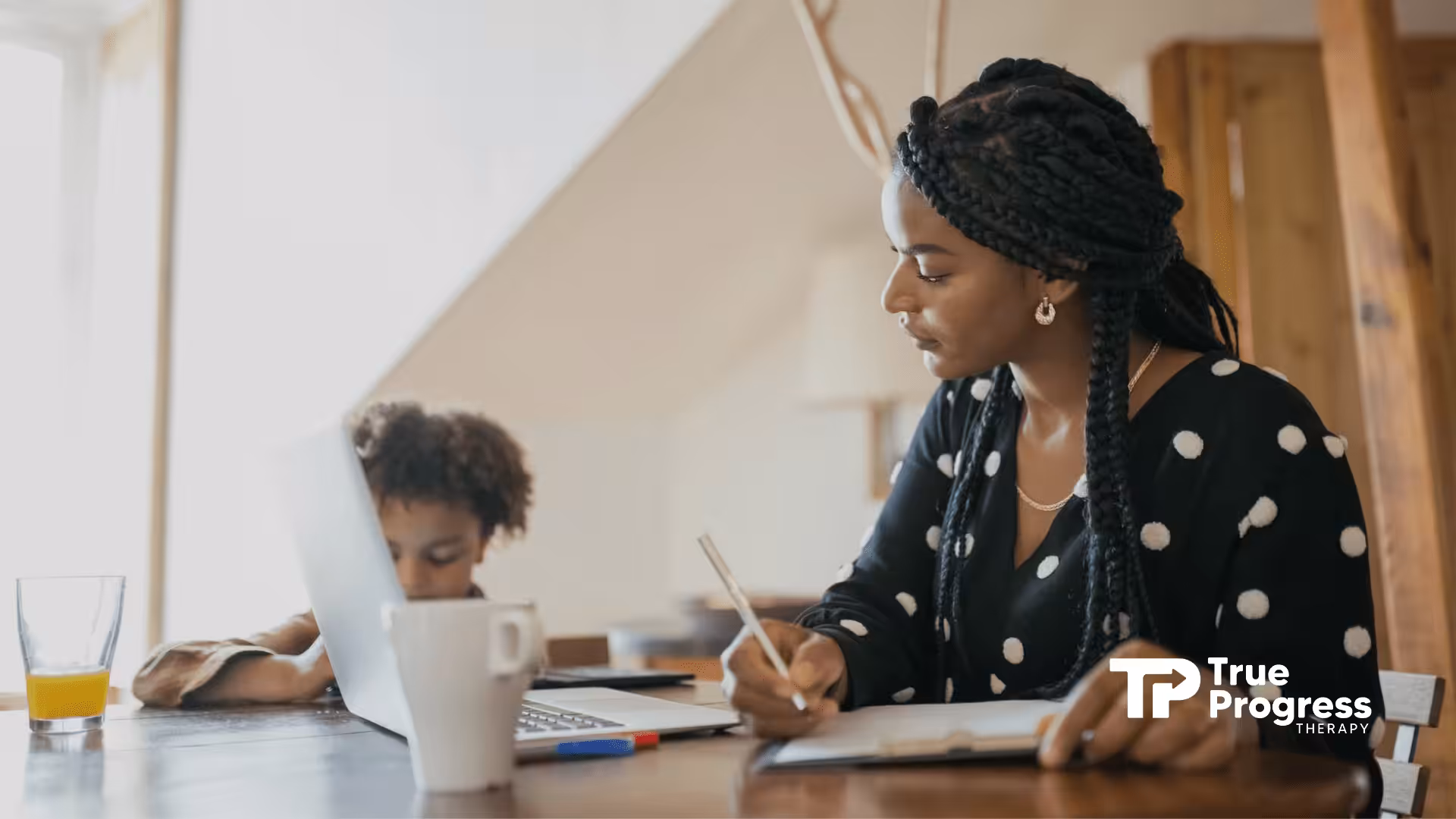 A BCBA and autistic child working together, the BCBA writing notes as the kid uses a laptop in NJ.