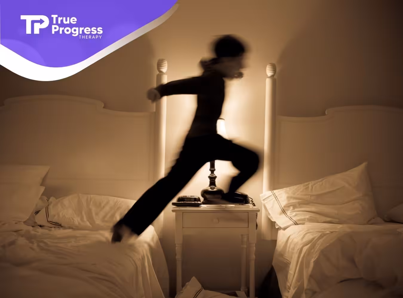 A little boy jumping between two beds.