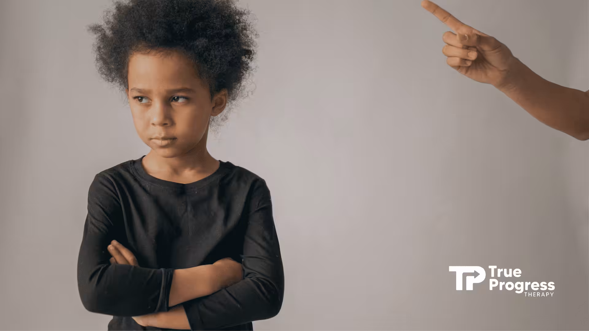 An autistic child with crossed arms looking away as an adult points a finger, punishing them in NJ.