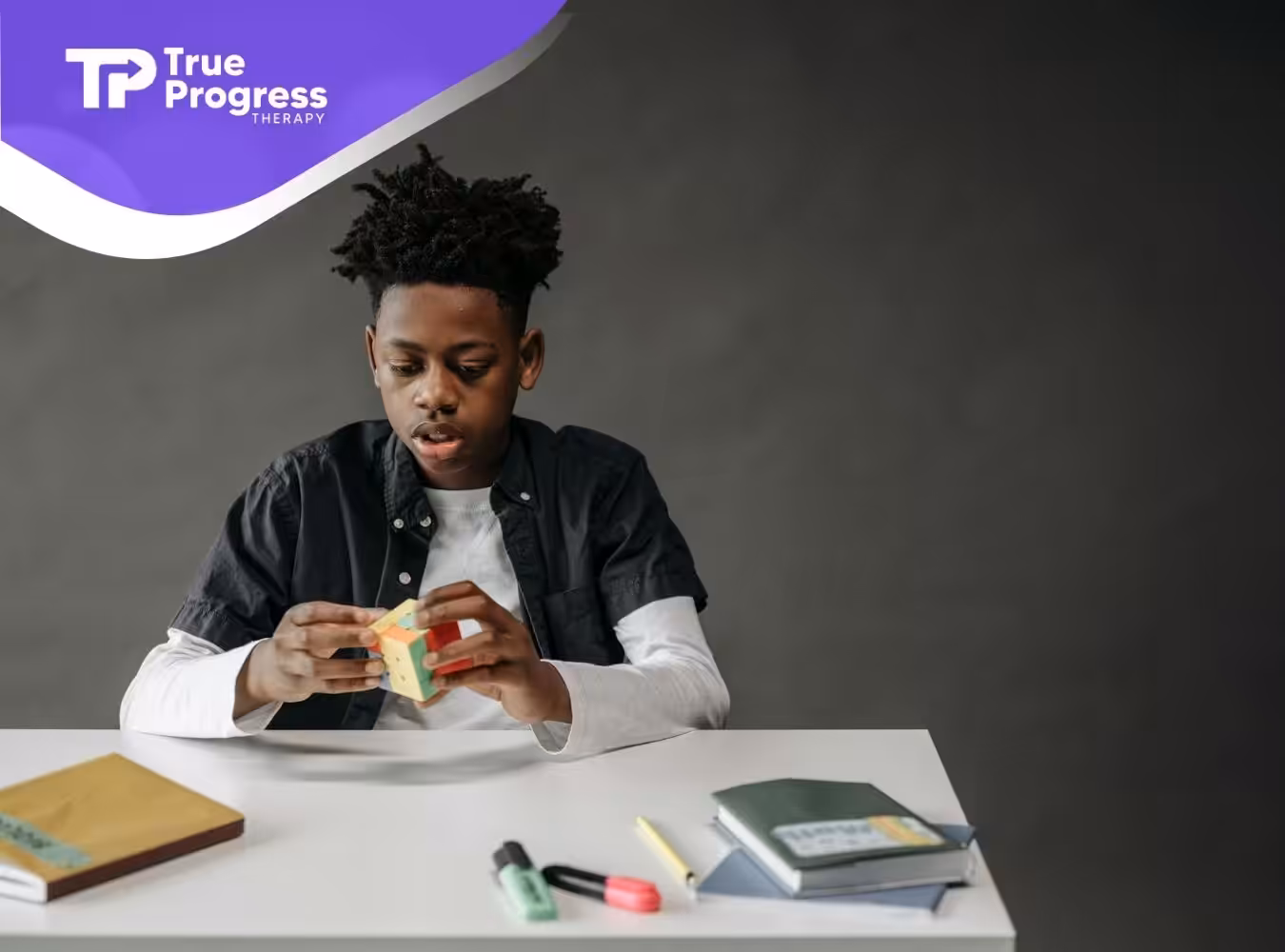 An autistic boy solving colorful cube puzzle at desk during in-home ABA therapy session in New Jersey.