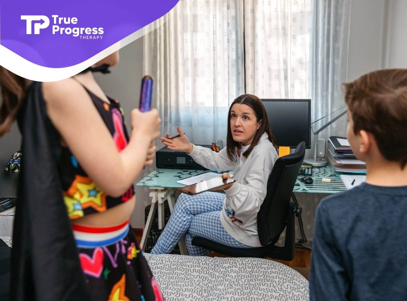 ABA therapist talking with two autistic children in a home office, guiding behavior & communication during a support session.