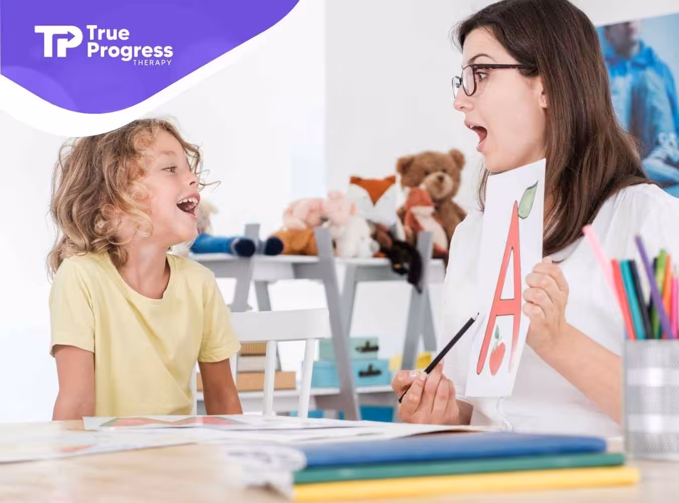 A smiling child and a woman engage in a language activity, holding a card with a large red letter "A." Toys and colorful items are visible in the background.