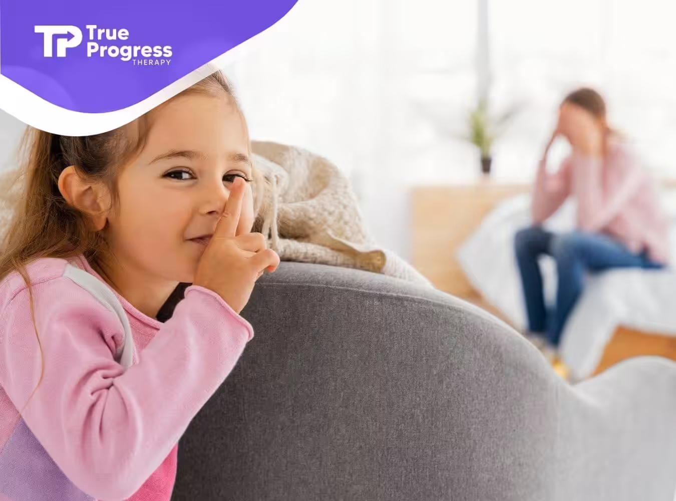 A smiling girl with autism holding her finger to her lips to signal quiet.