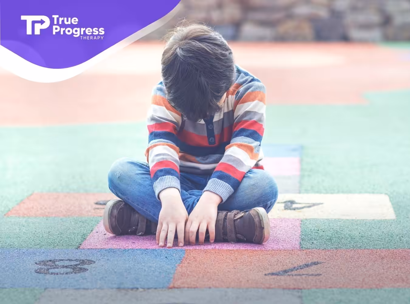 A sad kid sitting in the middle of a court.