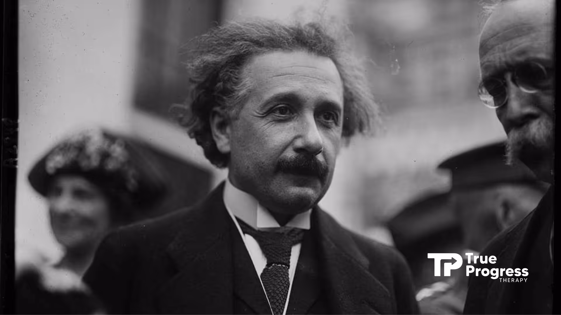 Black & white photo of Albert Einstein with disheveled hair, suspected of autism, looking thoughtful.