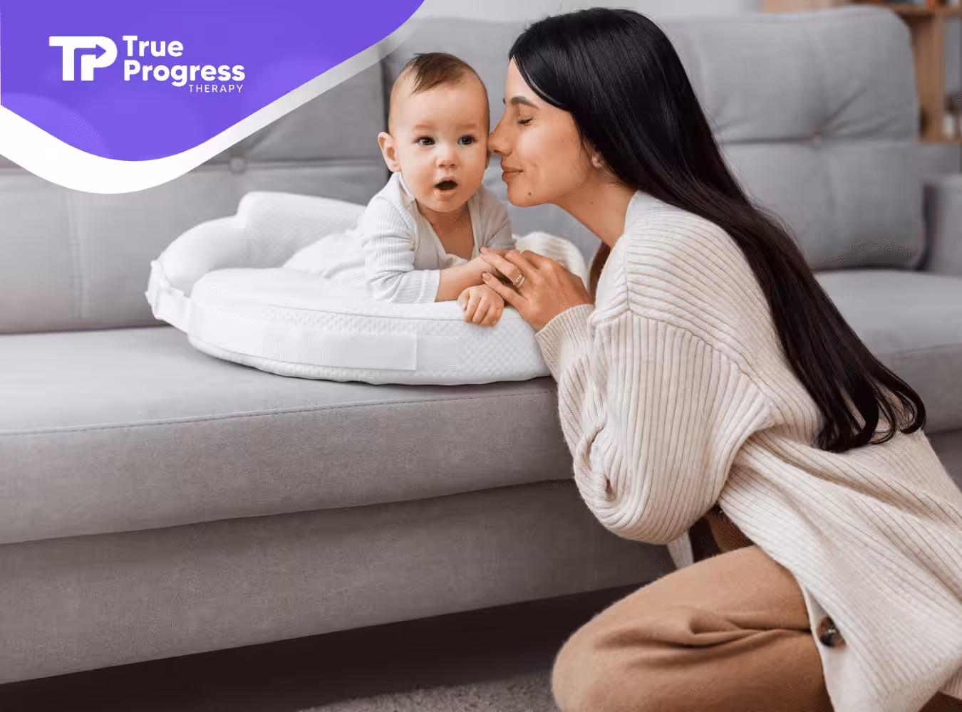 A mother is kissing her baby on a couch