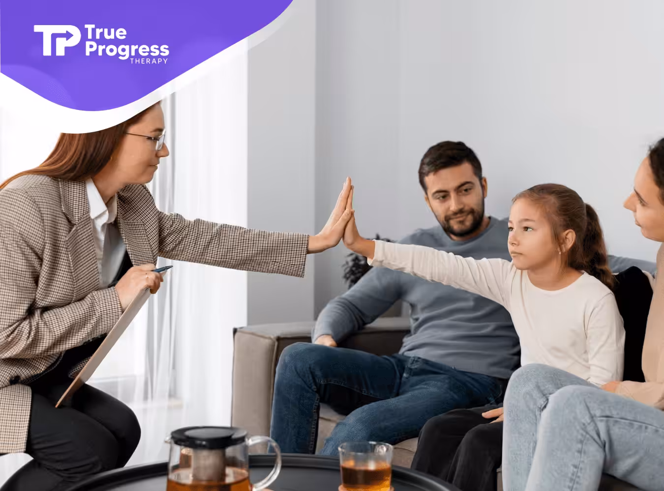 A therapist giving a high five to a girl during their autism family therapy.