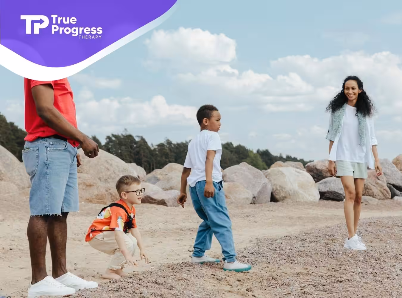 Parents with their autistic children enjoying a day at the beach with rocks and clear skies in NJ.