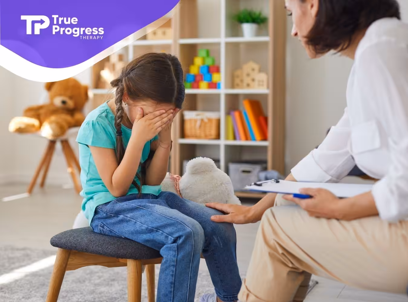 A little girl looking sad and comforted by her therapist.
