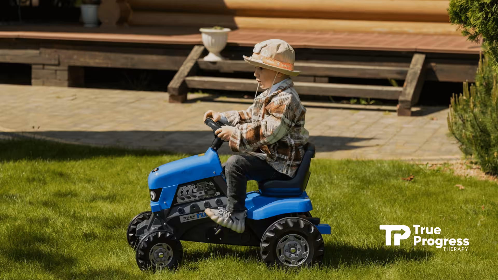 Young autistic boy riding a blue toy tractor on a grassy yard during in-home ABA therapy in New Jersey.