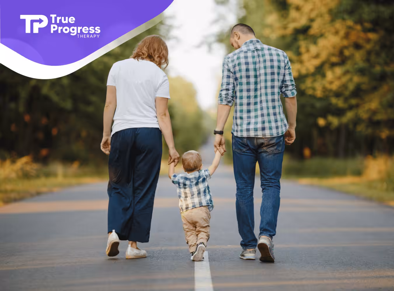 A child with autism is walking outdoors while being held by both his parents
