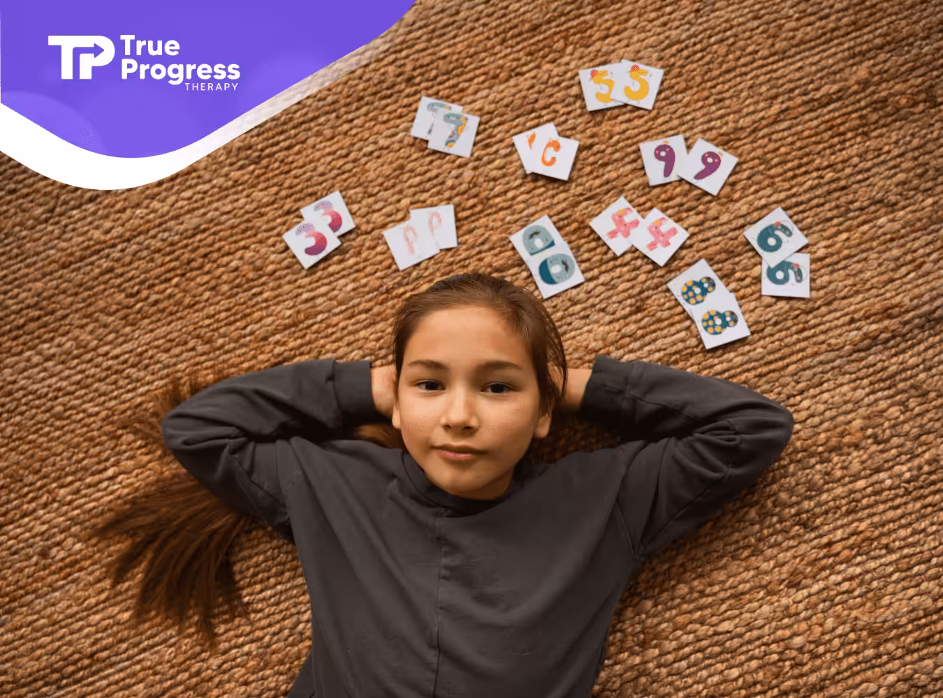 A girl with autism is laying on the floor with memory game cards