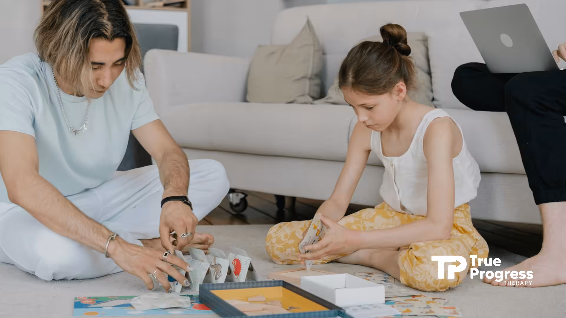 An ABA therapist and an autistic child are playing a board game together on the living room floor in NJ.