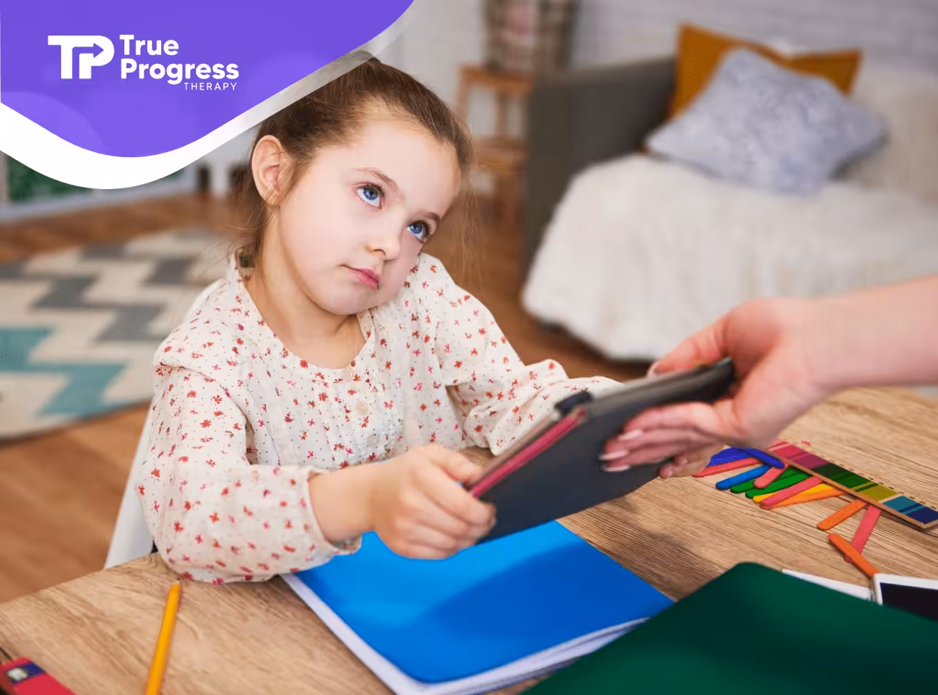 An autistic child looking at her parent while holding a mobile tablet