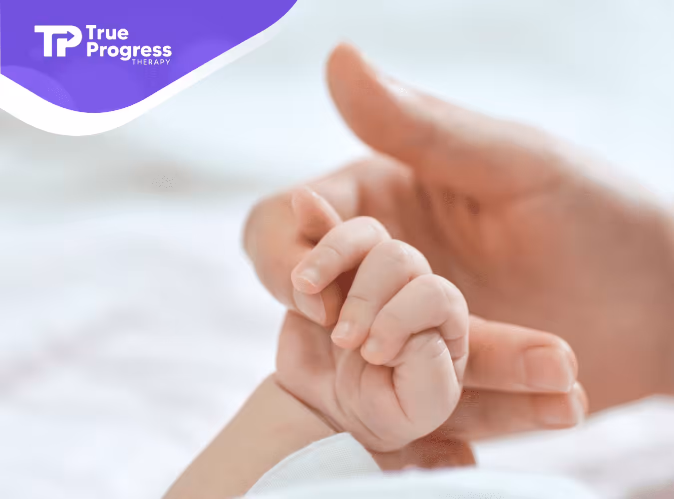 A BCBA holding a baby's hand during ABA therapy.