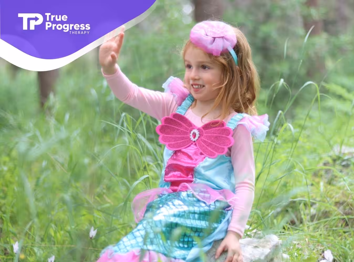 Young girl with regressive autism dressed as a mermaid waving while sitting outdoors in New Jersey.